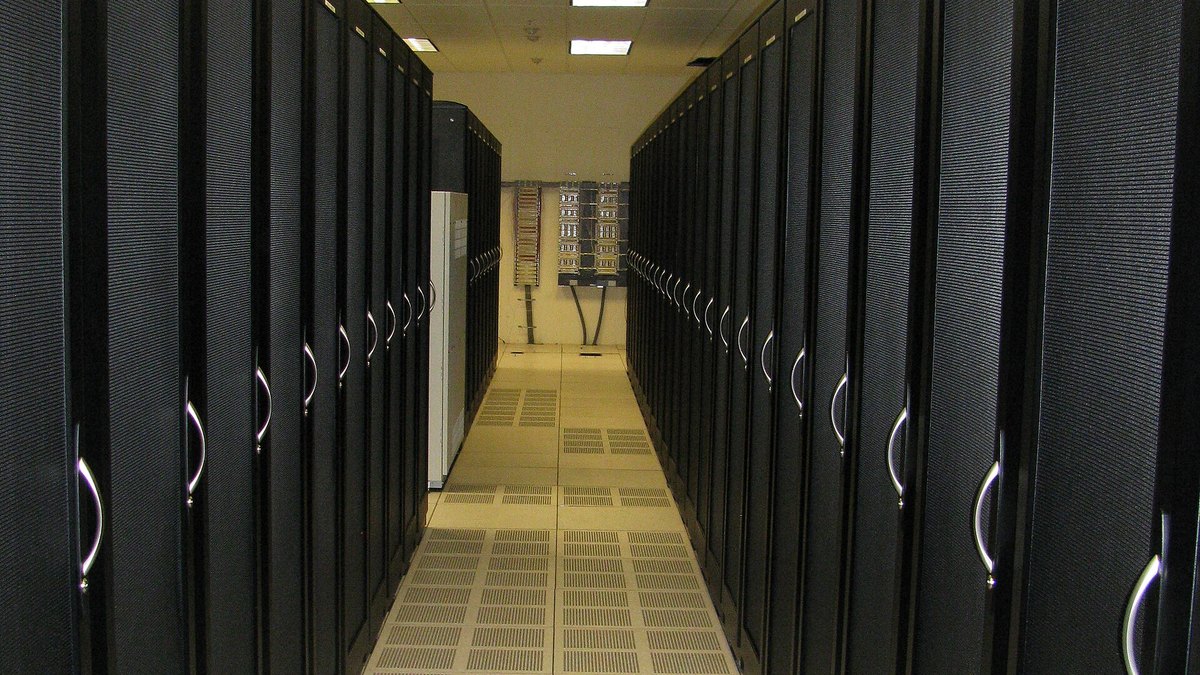 A long aisle between two rows of tall black server cabinets in a data center