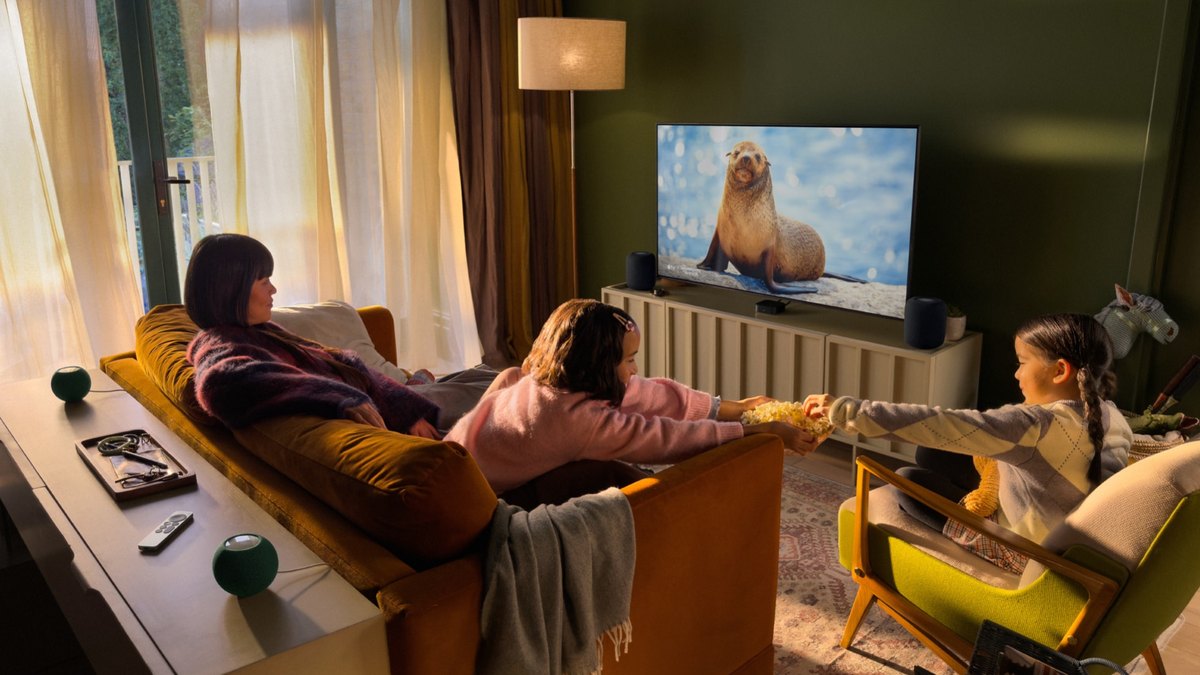 A family watching a TV with an Apple TV 4K and HomePod speakers in a living room