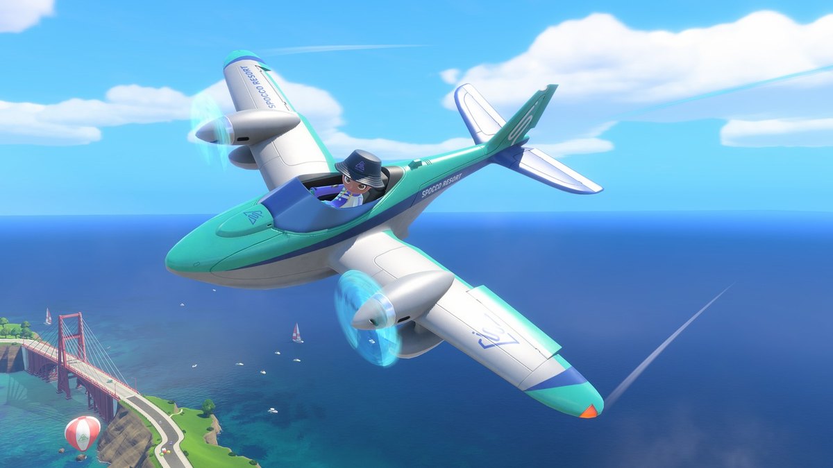 A teal prop plane flying over the water near a red suspension bridge in Nintendo Switch Sports Resort