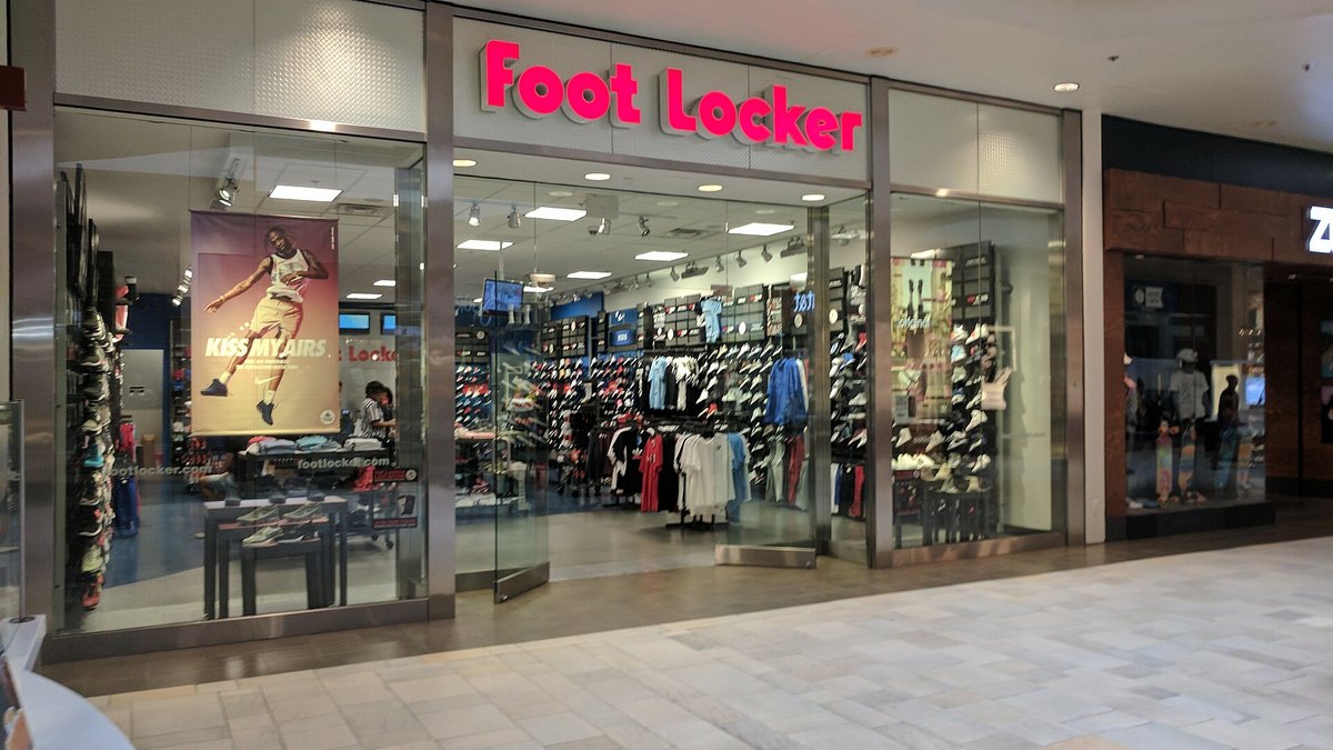 The glass-fronted entrance of a Foot Locker store in a shopping mall in Austin, Texas, with shoes and apparel on display inside