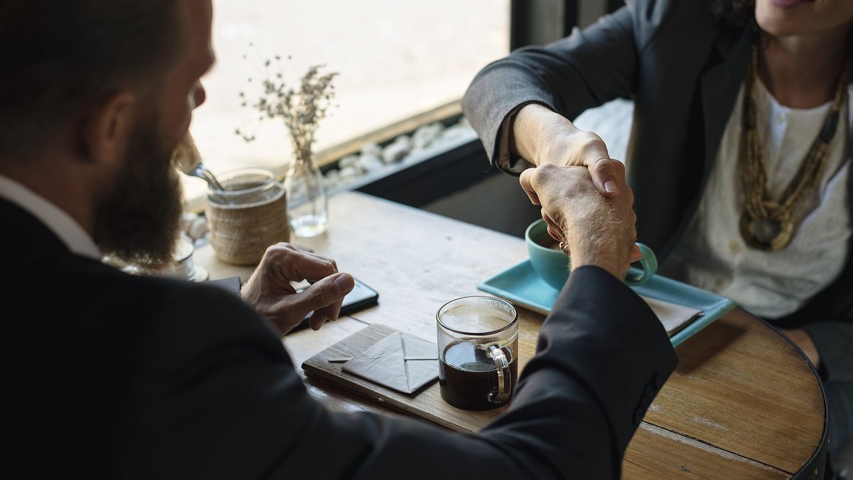 Two people shaking hands over coffee