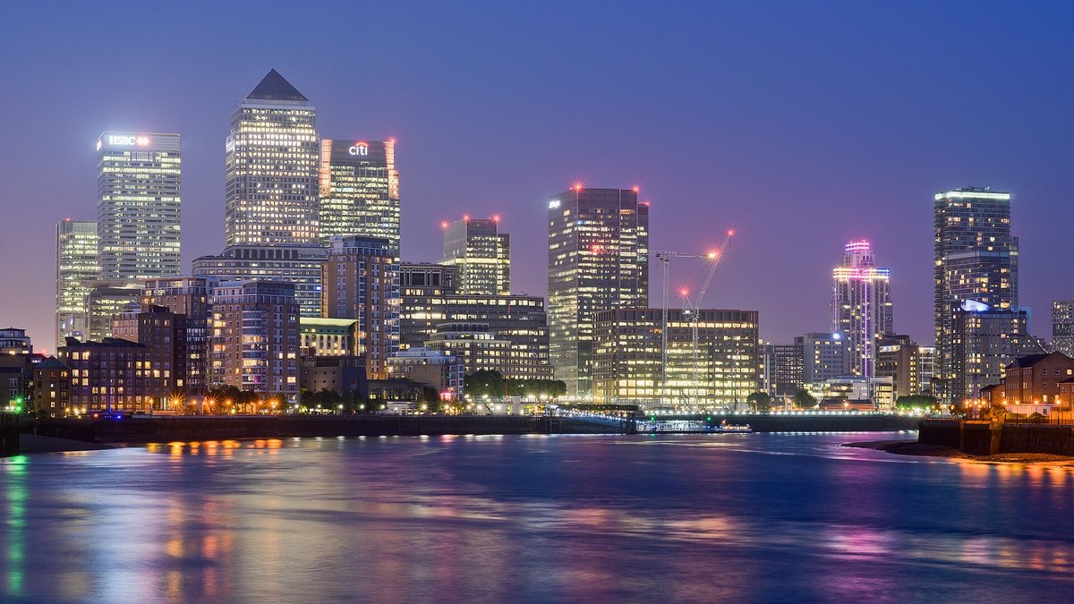 The towers of the Canary Wharf financial district lit at dusk across the River Thames in London