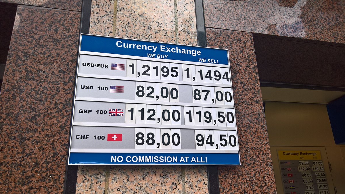 A blue and white currency exchange sign showing buy and sell rates for the dollar, euro, pound and Swiss franc on a granite wall in Amsterdam