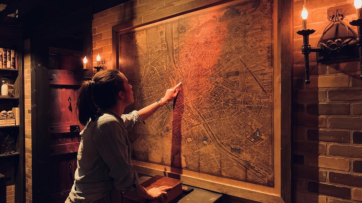 A player pointing at a large map on the brick wall of a themed escape room