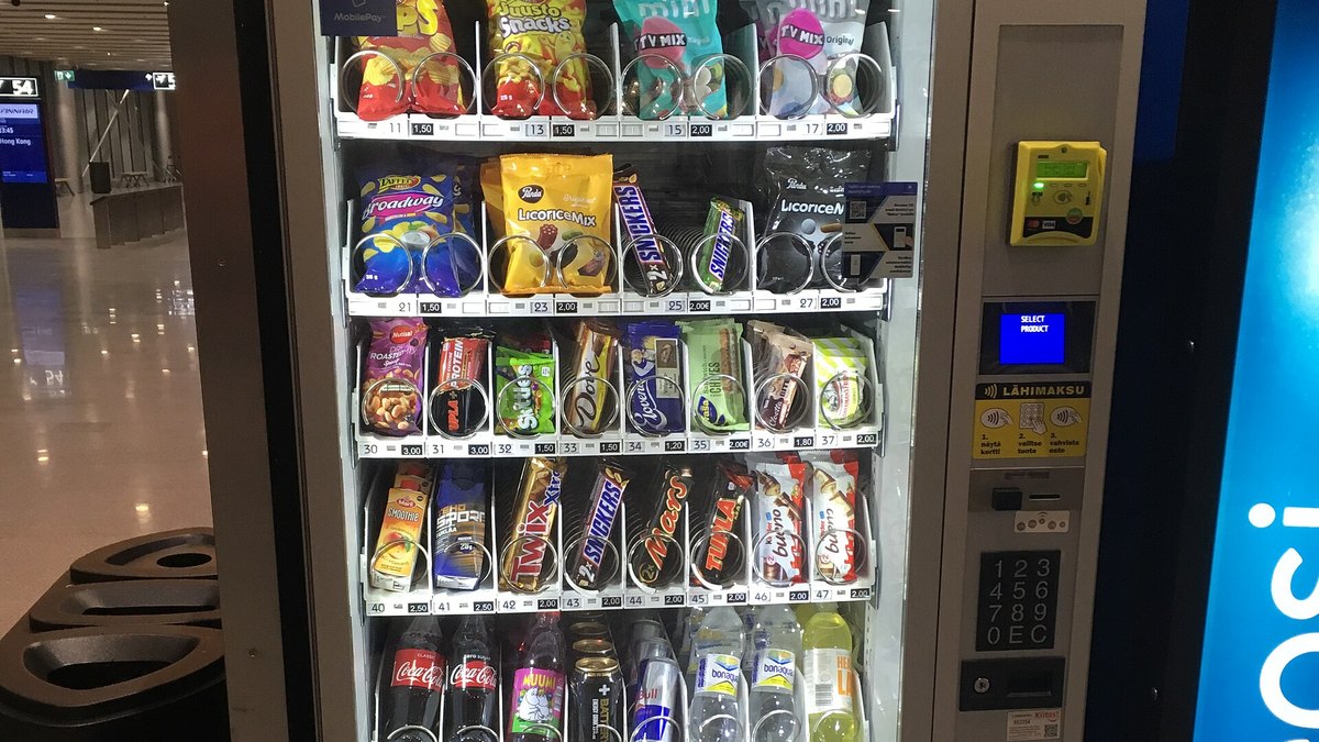 A snack and drink vending machine with a card reader at an airport